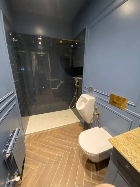 Baño azul con ducha y suelo de madera en espiga