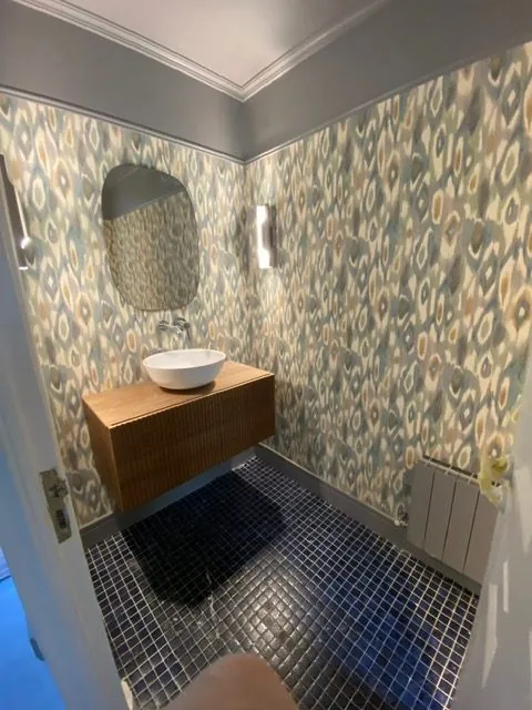 Baño con azulejo estampado, lavabo de piedra y suelo de mosaico