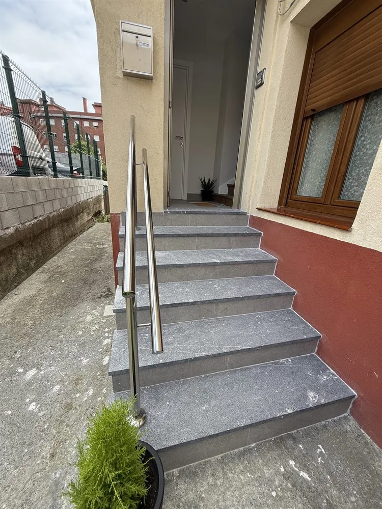 Escalera exterior de acceso a un portal, con barandilla nueva