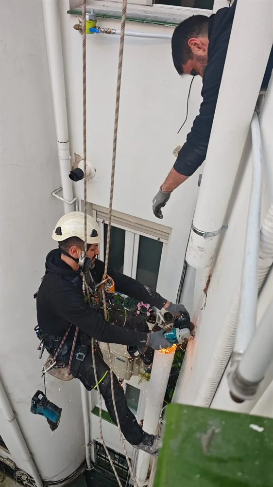 Operario suspendido con arnés trabajando en un patio interior