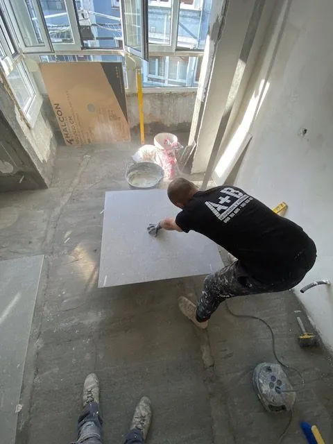 Operario aplicando el acabado sobre el suelo de una vivienda