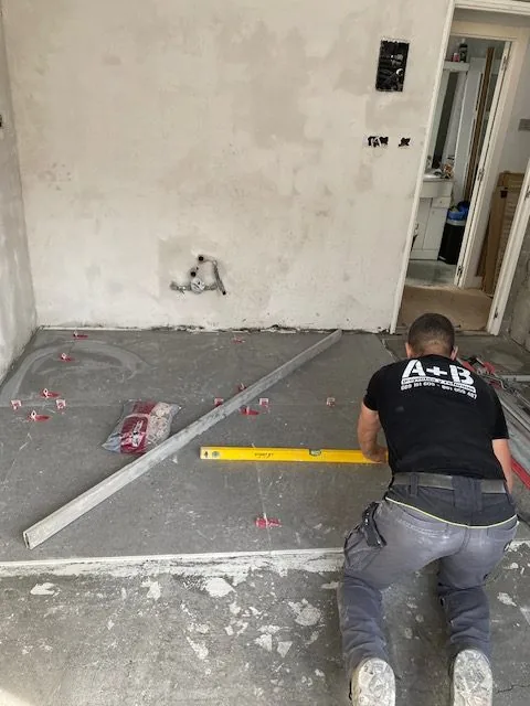 Operario de A+B tomando medidas sobre el suelo de una obra