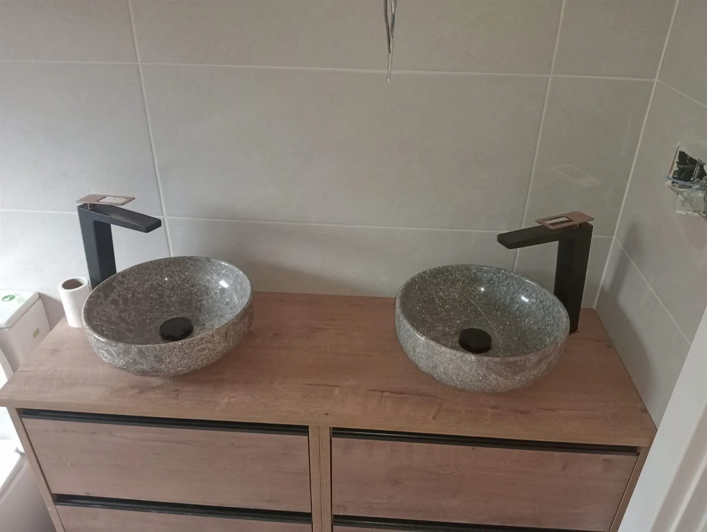 Detalle de dos lavabos de piedra sobre un mueble de madera