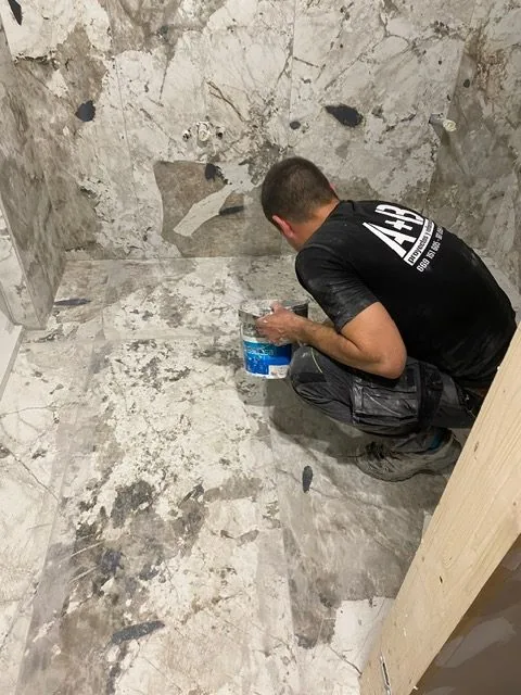Operario de Proyectos y Reformas A+B alicatando un baño